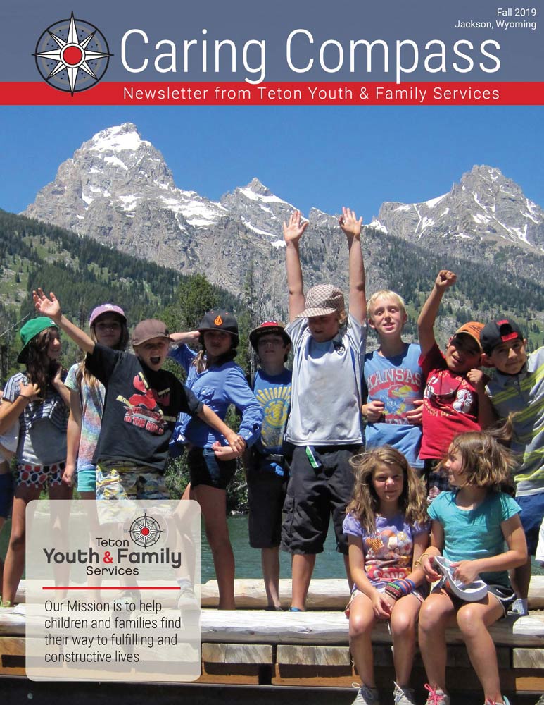Fall-2019-newsletter-cover - kids with hands up in the air in front of the tetons