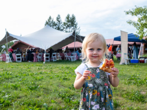 Little girl at picnic holding pizza