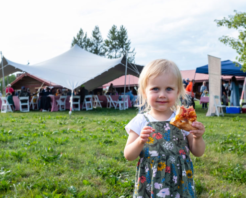 Little girl at picnic holding pizza